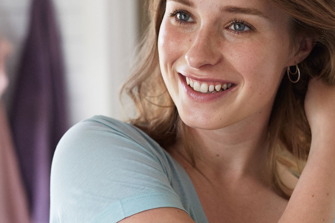 Tjej speglar sig i badrummet, ler stort.