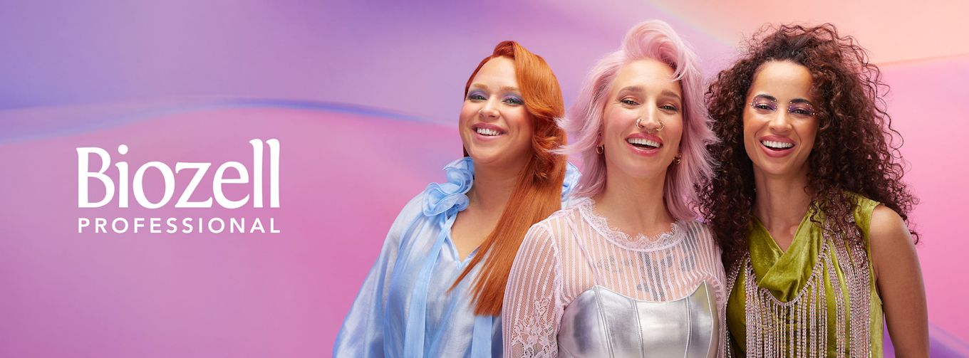 Tre leende kvinnor med färgglada frisyrer och smink poserar framför en pastellfärgad bakgrund, bredvid texten "Biozell Professional".