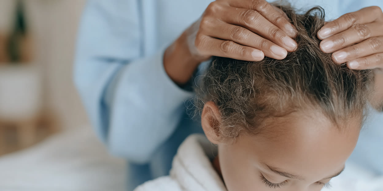 Barn tittar ner och en förälder står bakom och tittar om det finns löss i håret. Bilden är delvis skapad med AI.