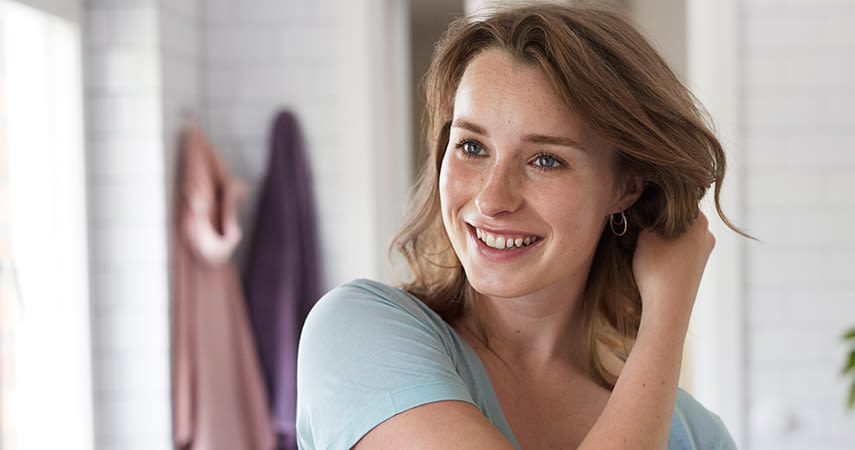 Tjej speglar sig i badrummet, ler stort.