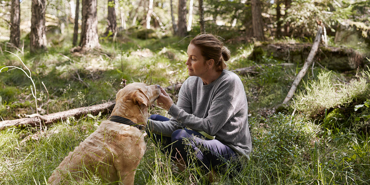 Kvinna och hund i skogen. 