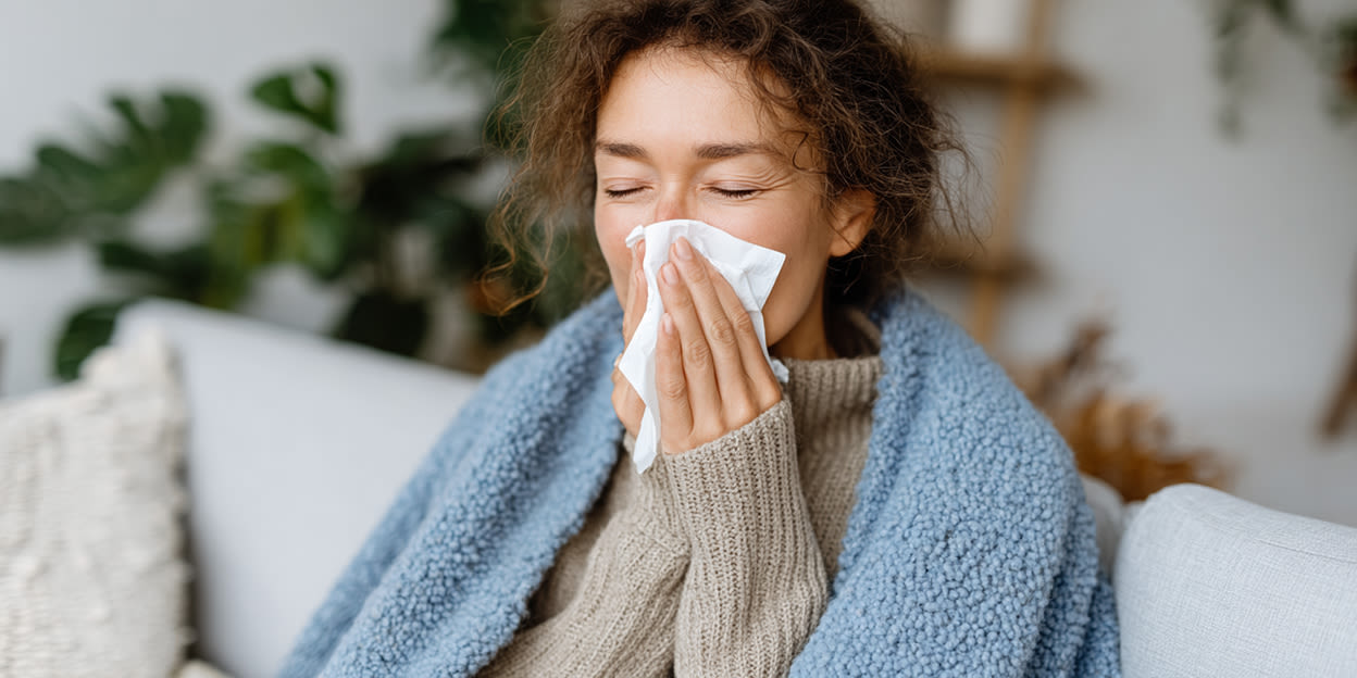 Kvinna sitter i soffan och snyter sig