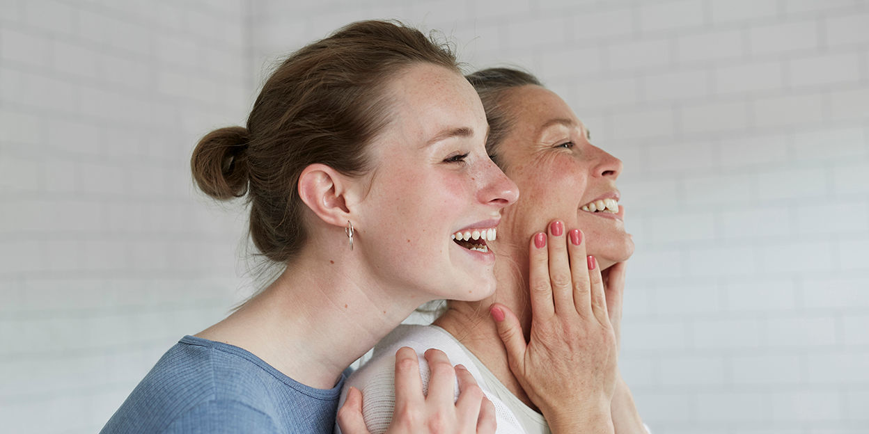 Kvinna och tjej står i badrummet och ler. 