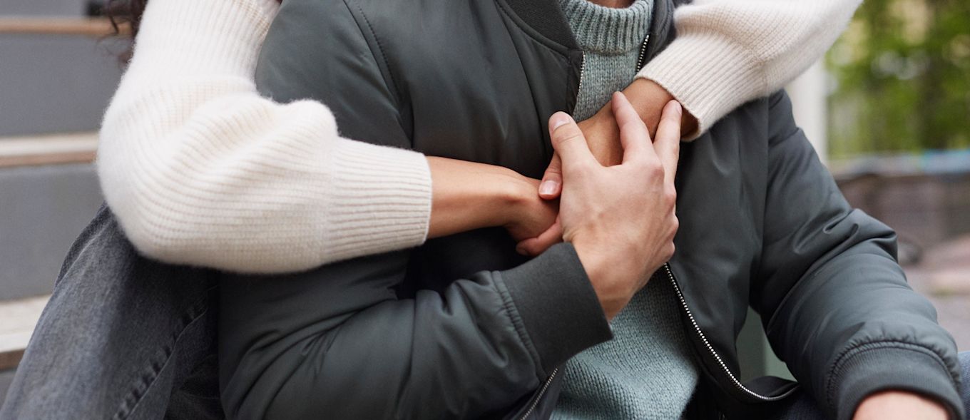 En kvinna kramar en kille bakifrån.