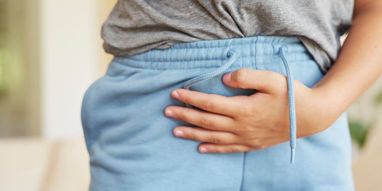 Tjej med mjukisbyxor som håller sig om magen. 