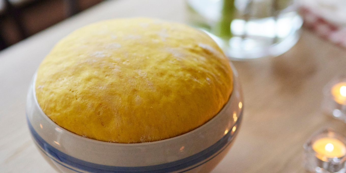 På ett bord står en keramikskål med en saffransdeg som jäser.