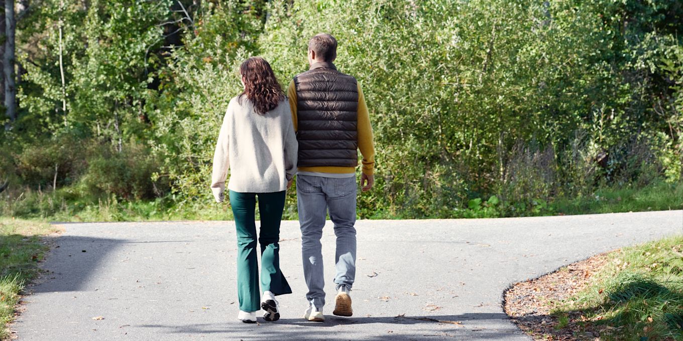 En man och en kvinna är ute och promenerar tillsammans en solig dag.