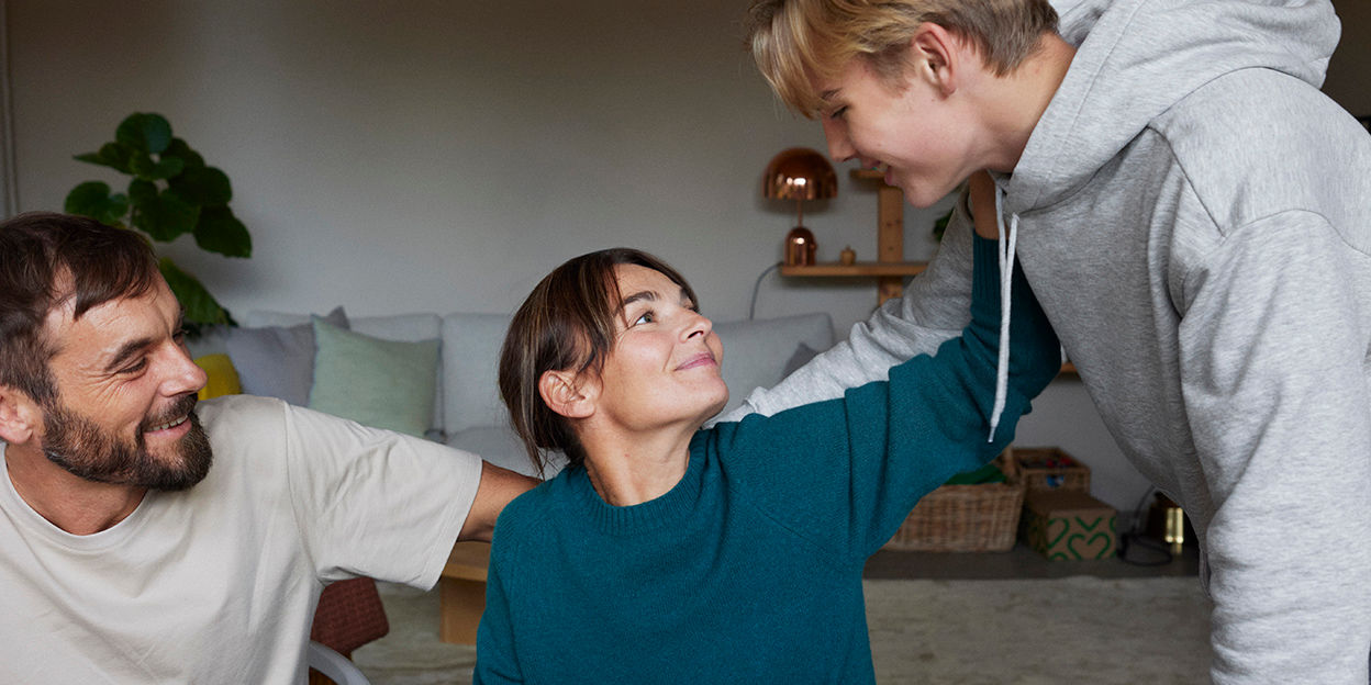Man, Kvinna och ung kille håller om varandra inomhus. 