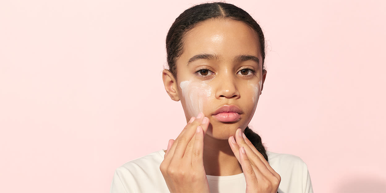 Tonåring smörjer in ansiktet och kollar rätt in i kameran.